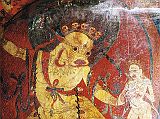 Tibet Guge 08 Tsaparang 05 Yamantaka Temple Yama To the right of the door is a painting of Yama (Tib. Shinje) riding a blue water buffalo. Yama is nude, has a buffalo head, wears a garland of human skulls, has an ornament shaped like a wheel on his breast, his right hand holds a sword topped with a skull, and his left hand holds a loop of rope. On the right is the fierce Dakini Simhaumukha. Snarling and roaring with a gaping large mouth on a white lion face, she stands fierce and menacing with two hands, with protruding fangs, curled tongue, two large round eyes and dark flowing hair. Her left hand clutches to the heart a white skullcup filled with blood. Photo - Th�ni: Westtibet.